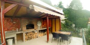 een patio met een tafel en stoelen en een open haard bij Jablanica villa with pool in Jablanica