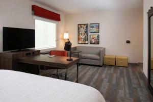 a hotel room with a bed and a desk and a television at Hampton Inn & Suites Buena Park in Buena Park