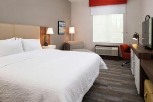 a hotel room with a white bed and a television at Hampton Inn & Suites Buena Park in Buena Park
