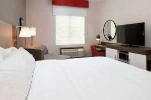 a hotel room with a white bed and a television at Hampton Inn & Suites Buena Park in Buena Park