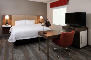 a hotel room with a bed and a desk and a television at Hampton Inn & Suites Buena Park in Buena Park