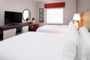 a hotel room with two beds and a flat screen tv at Hampton Inn & Suites Buena Park in Buena Park