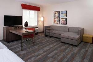 a hotel room with a couch and a television at Hampton Inn & Suites Buena Park in Buena Park