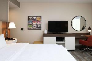 a hotel room with a bed and a desk with a television at Hampton Inn & Suites Buena Park in Buena Park
