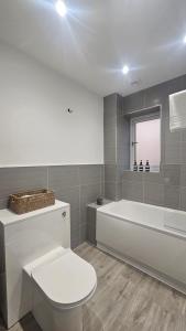 a bathroom with a white toilet and a bath tub at The Cowshed, SAV - Romney Sands Beach House in Littlestone-on-Sea