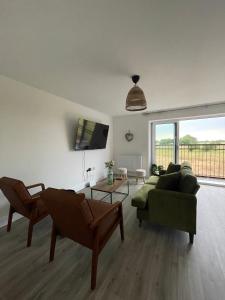 a living room with two chairs and a couch and a table at The Cowshed, SAV - Romney Sands Beach House in Littlestone-on-Sea
