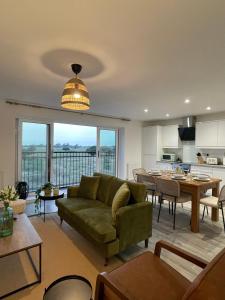 a living room with a green couch and a kitchen at The Cowshed, SAV - Romney Sands Beach House in Littlestone-on-Sea