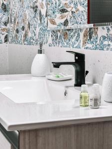 a white bathroom sink with a black faucet at Villa Gladyr in Lotzorai