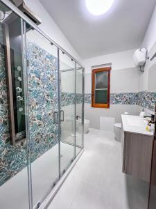 a bathroom with a glass shower and a sink at Villa Gladyr in Lotzorai