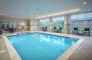 a swimming pool in a hotel with tables and chairs at Hilton Garden Inn Corning Downtown in Corning