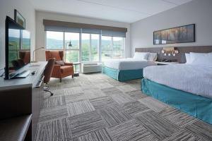 a hotel room with two beds and a desk at Hilton Garden Inn Corning Downtown in Corning