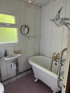uma casa de banho com uma banheira, um lavatório e um pássaro na parede em Madame Chalet em Seaton