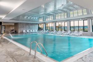 a large swimming pool with chairs in a building at Apartament Opal 34 Family & SPA in Dziwnów