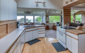 a kitchen with white cabinets and wooden flooring at The Boat House in Yachats