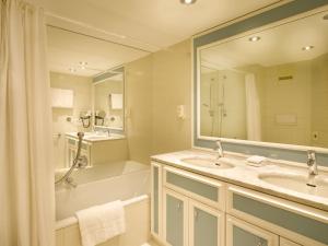 a bathroom with two sinks and a tub and a mirror at Seehotel Waltershof in Rottach-Egern