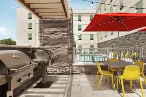 een patio met een grill en een tafel met gele stoelen bij Home2 Suites By Hilton Sarasota Bradenton Airport in Sarasota