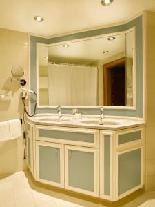 een badkamer met een wastafel en een grote spiegel bij Seehotel Waltershof in Rottach-Egern