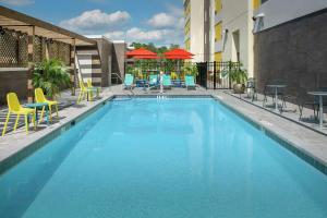 Home2 Suites By Hilton Lakeland في ليكلاند: مسبح مع كراسي وطاولات على مبنى