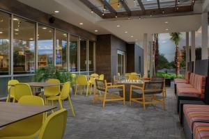 un restaurante con sillas amarillas, mesas y ventanas en Home2 Suites By Hilton Lakeland, en Lakeland