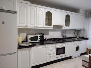 a white kitchen with white cabinets and a microwave at CU Apartamentos Pampin Ponte Do Porto in Ponte Do Porto