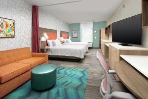 Habitación de hotel con cama, sofá y TV en Home2 Suites By Hilton Lakeland en Lakeland
