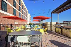 un patio con tavoli, sedie e ombrelloni rossi di Home2 Suites By Hilton Lagrange a LaGrange