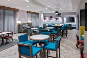 Hampton Inn Tampa Downtown Channel District في تامبا: غرفة انتظار مع طاولات وكراسي وتلفزيون