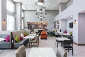 Hampton Inn & Suites Dallas East في دالاس: مطعم به طاولات و كنب و طاولات و كراسي