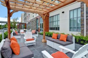 patio z kanapami i krzesłami pod drewnianą pergolą w obiekcie Hilton Garden Inn Princeton Lawrenceville w mieście Lawrenceville