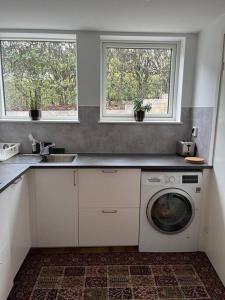 uma cozinha com uma máquina de lavar roupa e 2 janelas em Nice apartment near Mölndal Centrum / Göteborg em Mölndal