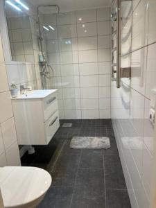 uma casa de banho branca com um lavatório e um chuveiro em Nice apartment near Mölndal Centrum / Göteborg em Mölndal