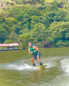 Un hombre está siendo tirado en una tabla de surf en el agua en Cabaña Privada o Casa Privada Tana, en Prado