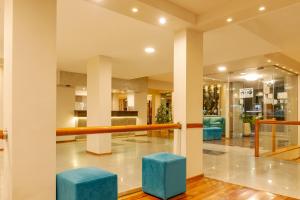 un hall avec tabourets bleus dans un bâtiment dans l'établissement Riviera Hotel & Spa, à Villa Carlos Paz