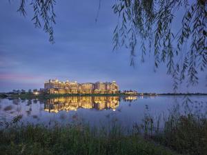 a large building sitting on top of a lake at night at Hilton Wenan in Langfang