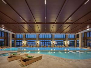 a large swimming pool in a hotel with chairs at Hilton Wenan in Langfang