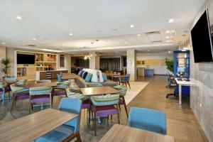 a restaurant with tables and chairs and a bar at Home2 Suites Plano Legacy West in Plano