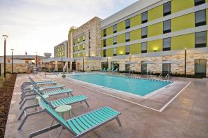 a pool with lounge chairs in front of a building at Home2 Suites Plano Legacy West in Plano