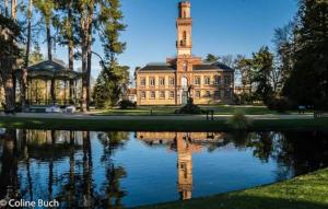 a building with a clock tower in front of a lake at Résidence Paul Bert in Tarbes