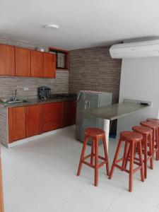 una cocina con armarios de madera, mesa y taburetes en Apartamento 10c Edf.Playa, en Santa Marta