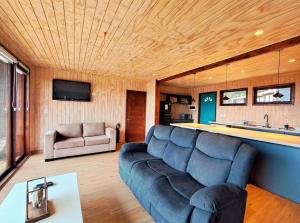 sala de estar con sofá azul y cocina en Lodge Tregualemu, en Cobquecura