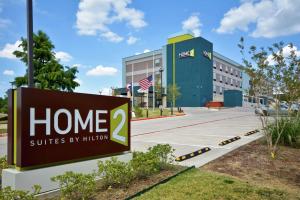 een bord voor een gebouw met een volkslied bij Home2 Suites By Hilton Bedford Dfw West in Bedford