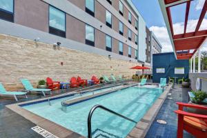 a swimming pool with chairs and a building at Home2 Suites By Hilton Bedford Dfw West in Bedford