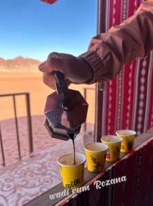 une personne prenant un verre à partir de deux tasses dans l'établissement Wadi rum Rozana camp, à Wadi Rum
