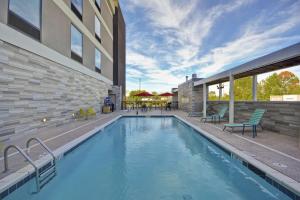 a swimming pool with chairs and a building at Home2 Suites By Hilton Clarksville Louisville North in Clarksville