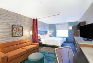 een hotelkamer met een bank en een bed bij Home2 Suites By Hilton Clarksville Louisville North in Clarksville