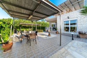 un patio con mesa y sillas bajo una pérgola en Grekodes Kera, seafront villa, en Kalyves
