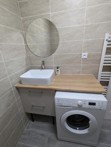 uma casa de banho com um lavatório, uma máquina de lavar roupa e um espelho. em Appart tout confort très proche RER A em Torcy
