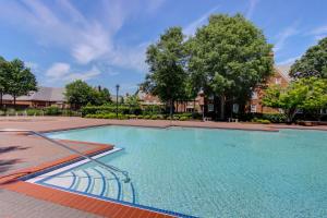 una gran piscina en un patio con árboles en The Founders Inn & Spa Tapestry Collection By Hilton, en Virginia Beach
