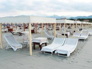 Hotel La Pigna في مارينا دي بيتراسانتا: مجموعة من الكراسي والطاولات والمظلات على الشاطئ
