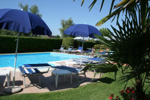 a swimming pool with blue umbrellas and lounge chairs next to it at Hotel Bolero in Sirmione